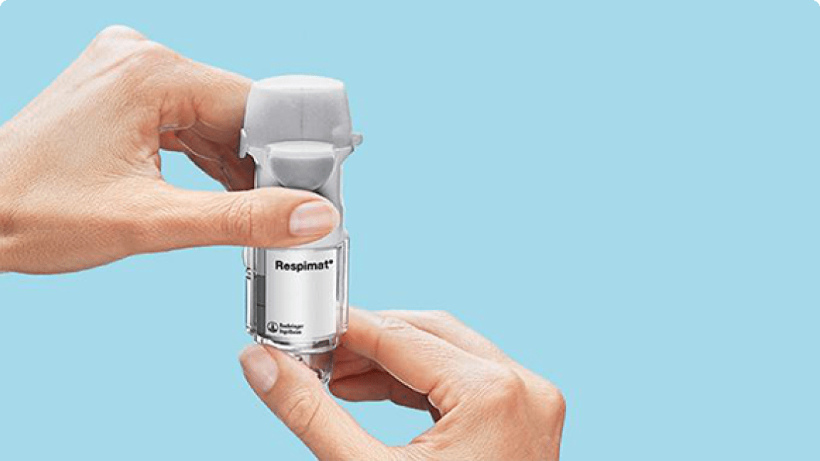 Respimat je držaný v rukách ukazujúc ako sa vymieňa náplň